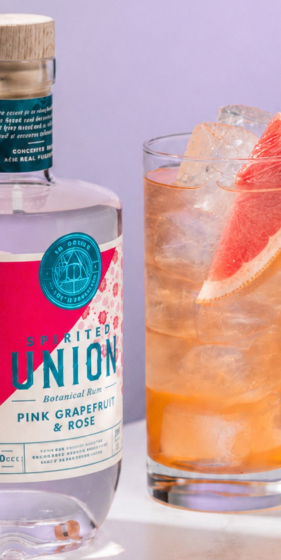 Rum Paloma met grapefruitpartje naast een fles Spirited Union Pink Grapefruit & Rose